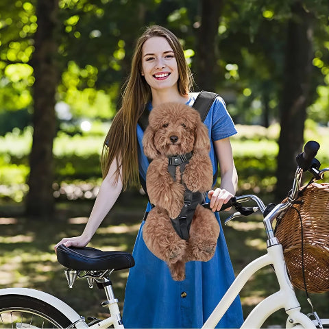 une cycliste qui sourit avec son chiot qui se repose dans le sac a dos chien