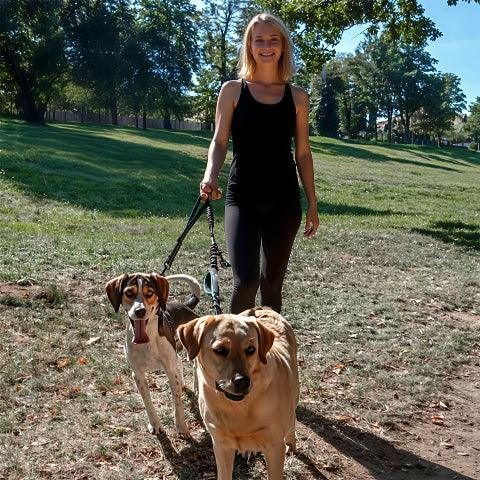 une fille qui se promene avec ses deux chiens avec la laisse double chien double corde bleu ciel